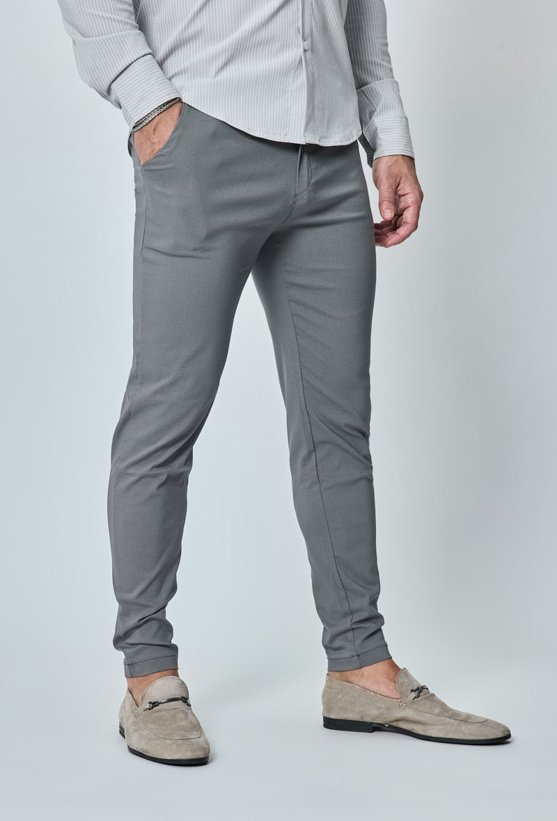 Donkergrijze slim fit chino broek van opzij, model met hand in zak.