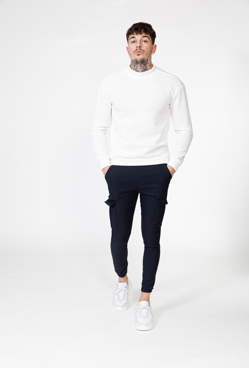 Man draagt marineblauwe cargo broek met wit shirt, full-body foto.