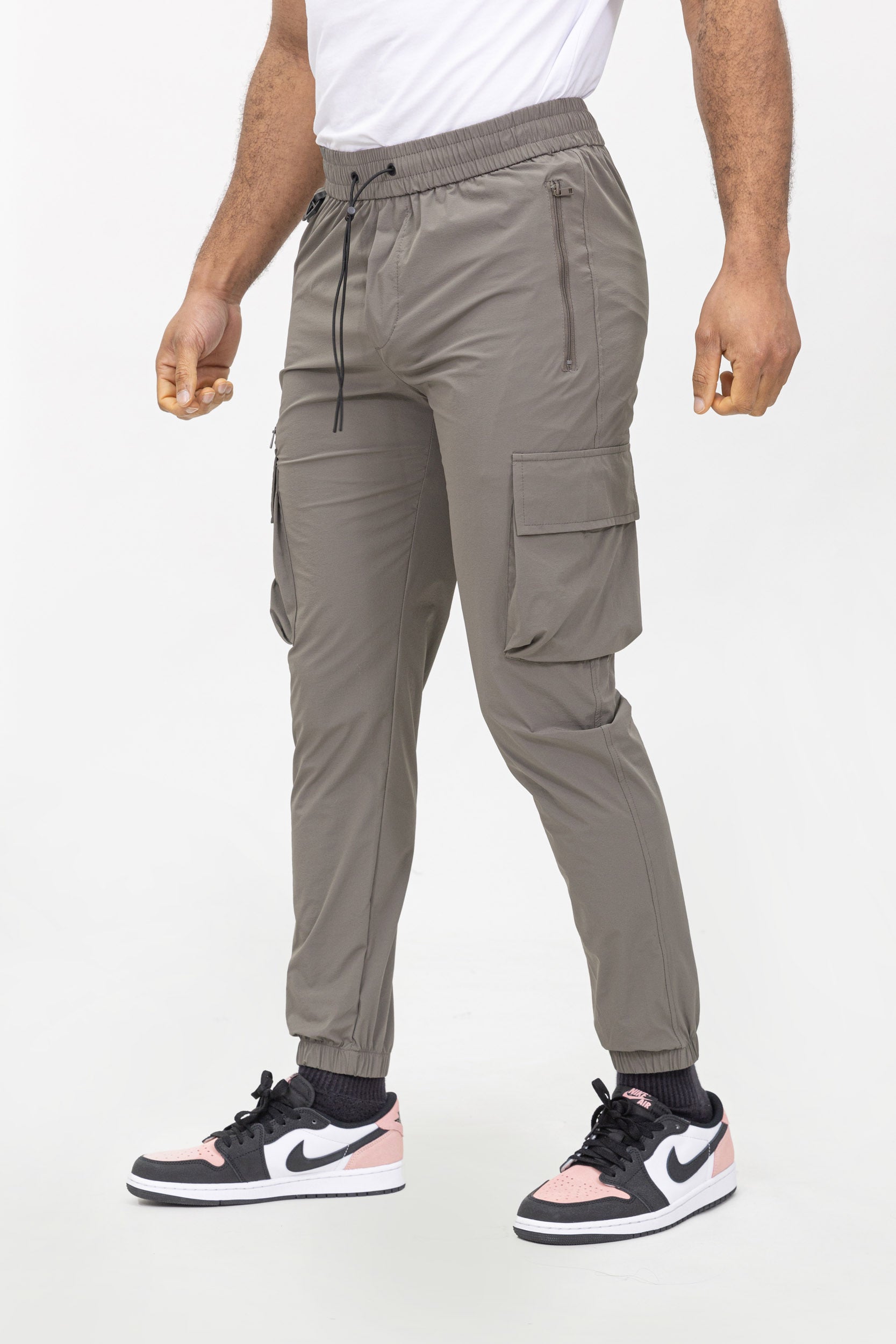 Man draagt taupe jogger cargo broek met elastische taille en cargozakken, schuin vooraanzicht.