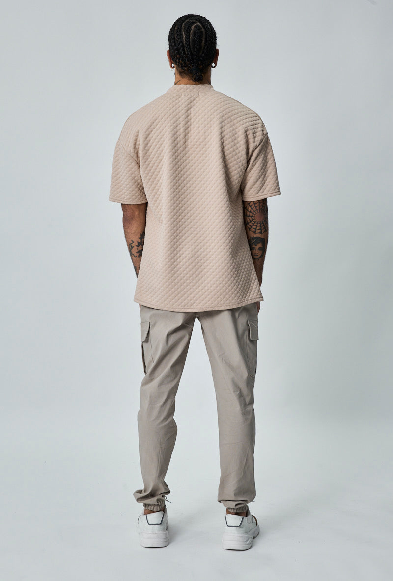 Achteraanzicht van beige heren cargo broek met rechte pasvorm en elastische taille.
