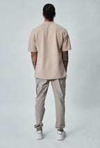 Achteraanzicht van beige heren cargo broek met rechte pasvorm en elastische taille.