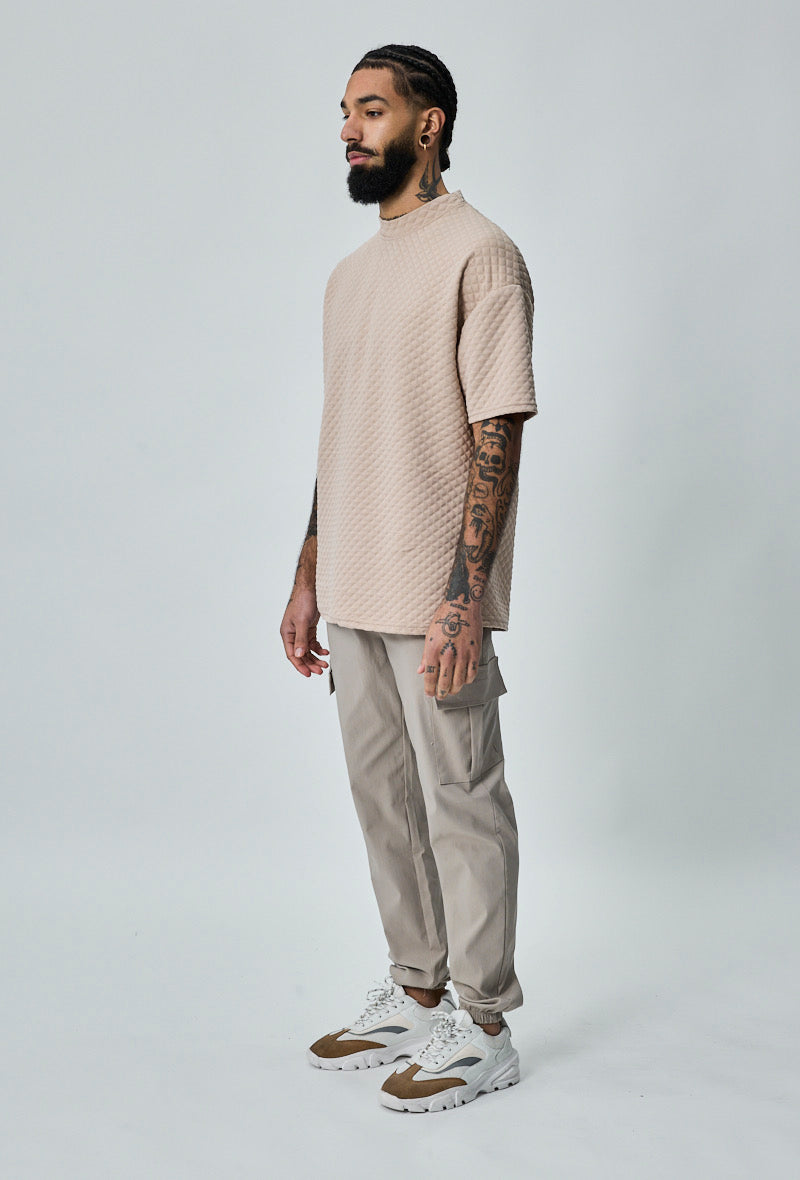 Model draagt beige heren cargo broek met cargozakken – zijaanzicht.