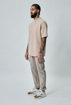 Model draagt beige heren cargo broek met cargozakken – zijaanzicht.