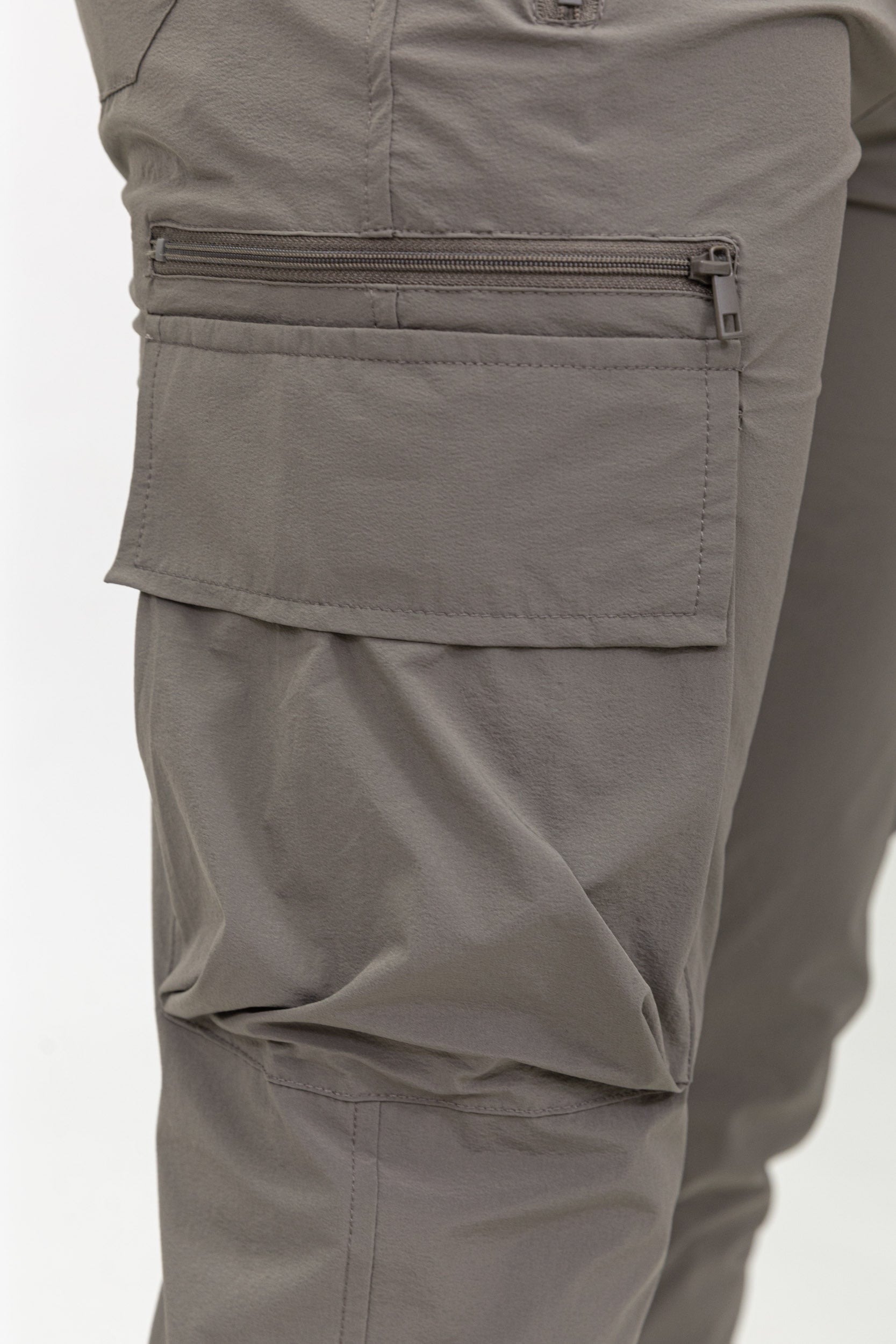 Close-up van cargozak met rits op taupe jogger cargo broek, gedetailleerde stof en afwerking.