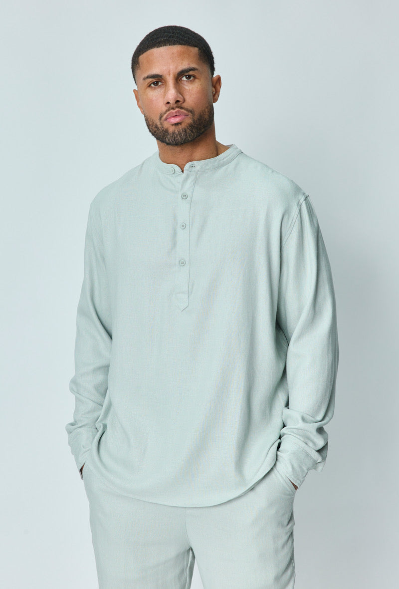 Herenmodel met lichtblauwe linnen set, handen in de zakken, neutrale achtergrond.