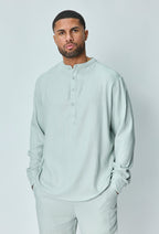 Herenmodel met lichtblauwe linnen set, handen in de zakken, neutrale achtergrond.