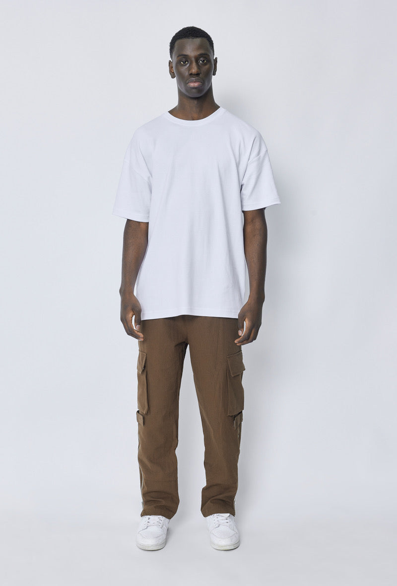 Volledige outfit met wit oversized T-shirt, bruin broek en witte sneakers, frontaal zicht.