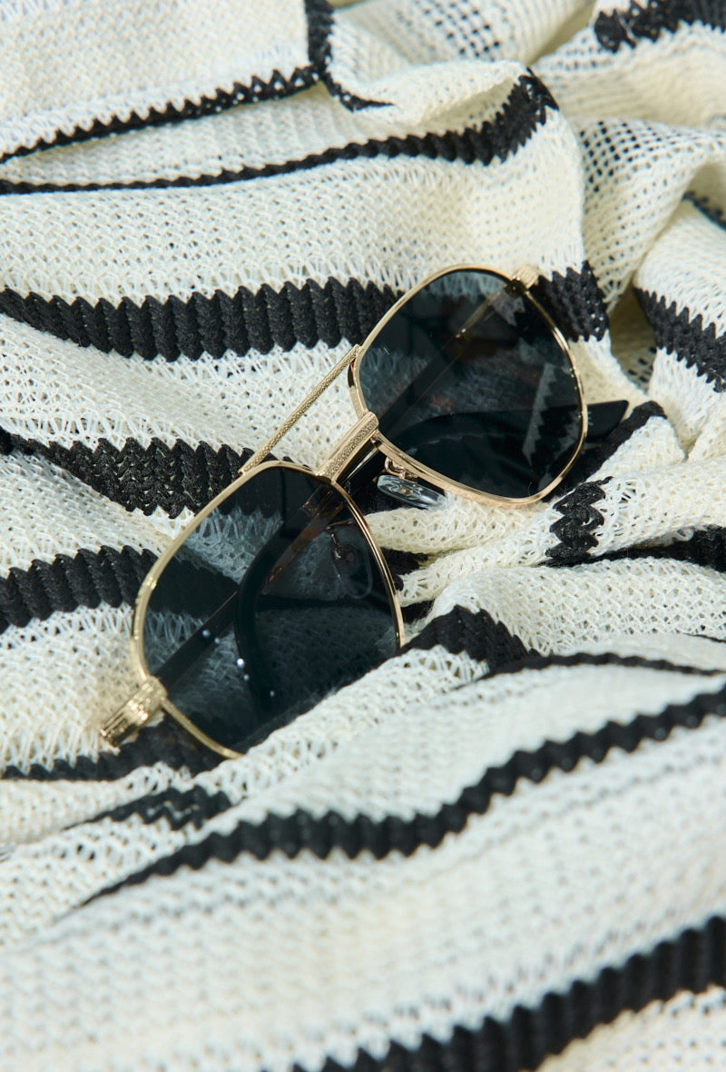 gouden zonnebril met donkere glazen gestyled op stof - lifestyle foto
