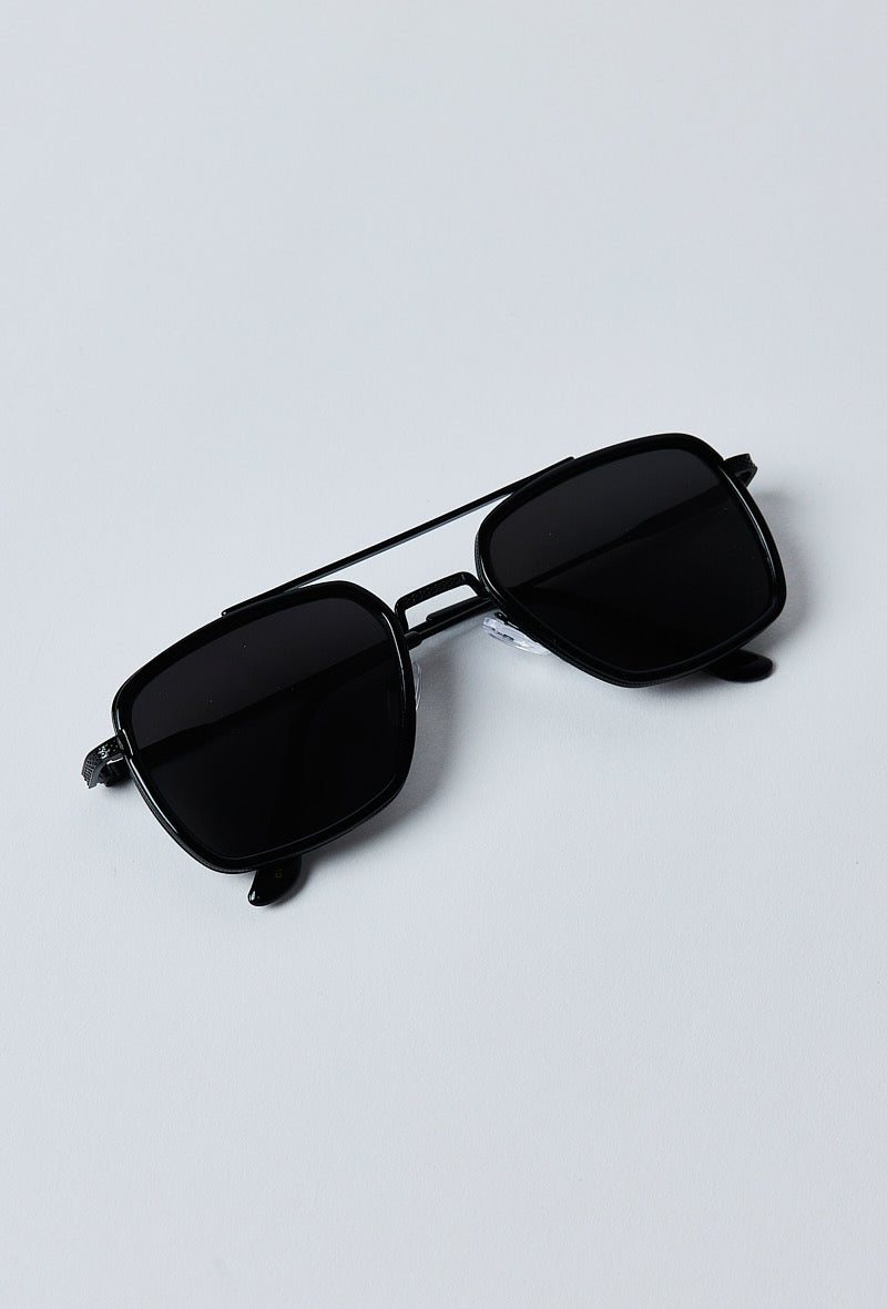 Zwarte zonnebril opgevouwen liggend op een witte achtergrond - moderne minimalistische stijl