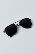 Zwarte zonnebril opgevouwen liggend op een witte achtergrond - moderne minimalistische stijl