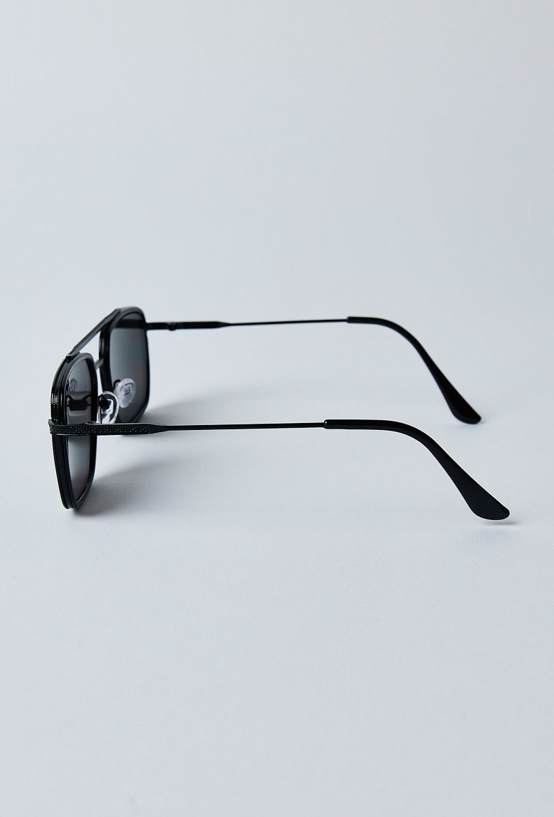 Zijkant van een matte zwarte zonnebril met dun metalen frame en verstelbare neussteun