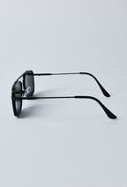 Zijkant van een matte zwarte zonnebril met dun metalen frame en verstelbare neussteun